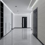 Wide corridor in modern house with white tiled walls and floor black wooden doors and shelves for storage built in wall