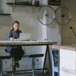 Woman working remotely on laptop with coffee cup in loft