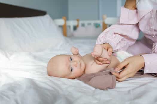 Crop mother dressing cute newborn baby