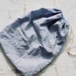 Empty textile blue bag with drawstrings placed on table in light room