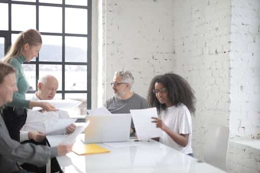 Focused multiracial coworkers of different ages in casual clothes brainstorming on new business ideas and company strategy while sitting at table in creative workspace