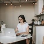 Focused young businesswoman using laptop at home