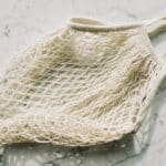 From above view of simple cotton recycling mesh bag placed on marble table in light room