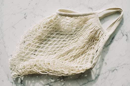 From above view of simple cotton recycling mesh bag placed on marble table in light room