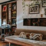 Interior of stylish living room with comfortable couch placed near shelf with collection of vintage vinyl records and wooden cabinet decorated with classic table lamp