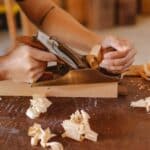 Man planing wooden plank with manual tool