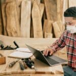 Man Using a Laptop at a Wood Workshop