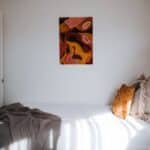 Soft bed with cotton blanket gray plaid and beige cushions placed in light room with white walls and picture in sunlight