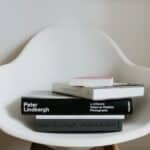 Stack of modern art books on white chair in room