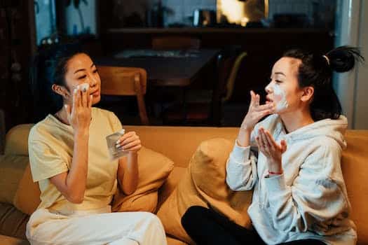 Woman in White Sweater and Black Pants Sitting on Brown Couch