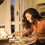 Young woman painting on paper at workplace