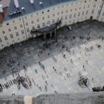 From above of travelers on square in front of aged vintage panoramic exploring sightseeing and studying place in daylight