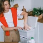 Happy woman sorting trash in bin