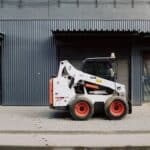 Small truck parked near warehouse on sidewalk on street