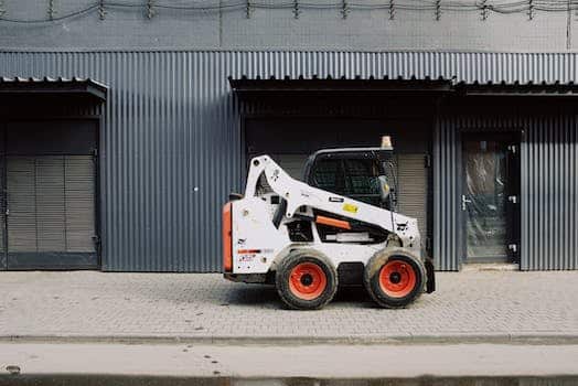 Small truck parked near warehouse on sidewalk on street