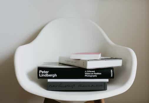 Stack of modern art books on white chair in room