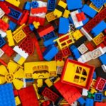 Top view of various pieces of colorful plastic construction toys scattered on wooden floor as abstract background