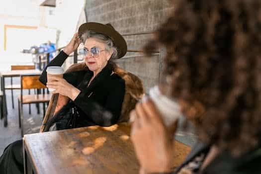 Woman in Black Long Sleeve Shirt Sitting on Chair With Coffee