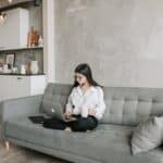 Woman Sitting On Sofa While Working At Home