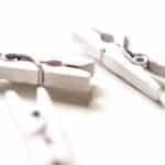 Closeup of white wooden clothespins with shadow on white background in bright light