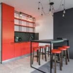 Creative design of kitchen with table and stools under light bulbs in house with fridge and mirrors on closet doors