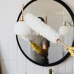 Crop woman dusting lamp during housework