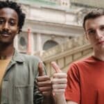 Positive young multiracial guys demonstrating thumbs up sign at camera