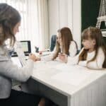 Woman Teaching Girls Sitting by the Table