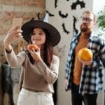 A Couple Holding Pumpkins While Taking Selfie Photo