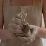 Crop faceless woman kneading clay in workshop