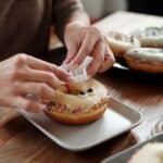 Person Putting A Plastic Vampire Teeth On A Donut