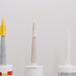 Set of various plastic tubes with glue for renovation works in workshop against white background