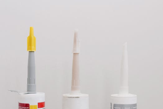 Set of various plastic tubes with glue for renovation works in workshop against white background