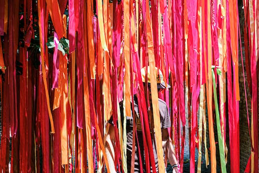 Unrecognizable man walking near multicolored ribbons decorating courtyard