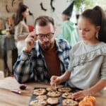 A Girl Decorating Cookies With Her Father