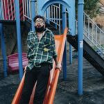 A Man Leaning on the Playground Slide