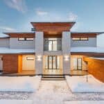 Backyard view of new modern luxurious cottage house with stone and wooden facade and illumination in winter countryside