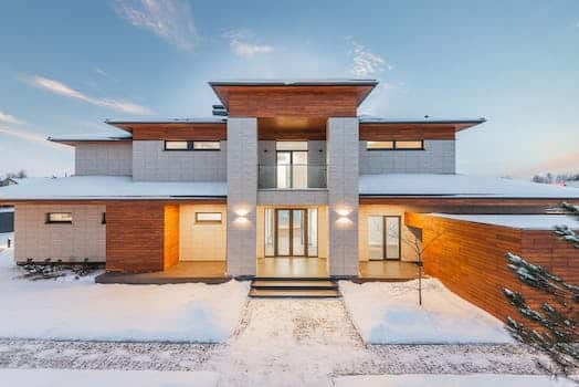 Backyard view of new modern luxurious cottage house with stone and wooden facade and illumination in winter countryside