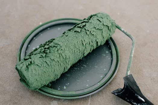 High angle of wet dirty roller for painting on plastic cap from paint on floor