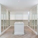 Interior of spacious walk in closet with mirrored furniture and bright lamps