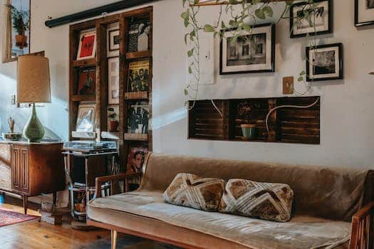 Interior of stylish living room with comfortable couch placed near shelf with collection of vintage vinyl records and wooden cabinet decorated with classic table lamp