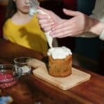 Person Holding Piping Bag with White Icing