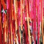 Unrecognizable man walking near multicolored ribbons decorating courtyard