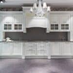 Interior design of spacious light kitchen with white cupboards and shelves with various kitchenware