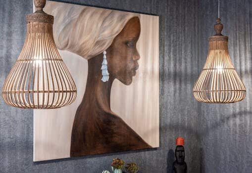 Painting of African woman on wall between shiny lamps