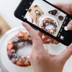 Woman hand taking photo on smartphone of delicious decorated cake