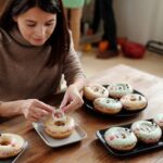 Woman Placing A Plastic Fang On A Donut